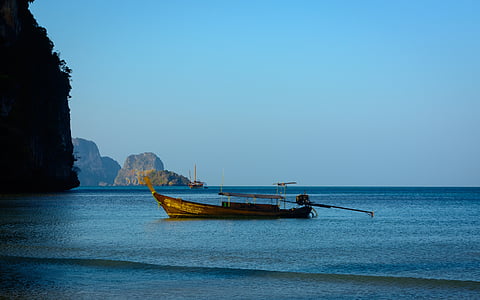 brown boat on body of water near island during daytime thumbnail