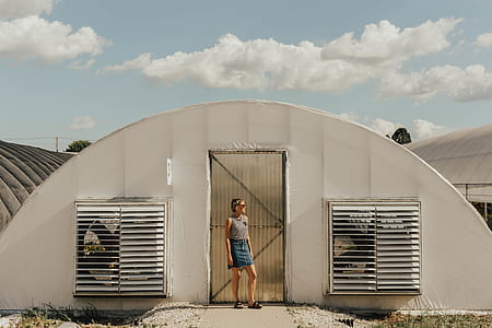woman standing near white and gray half-moon wall outside during daytime photography thumbnail