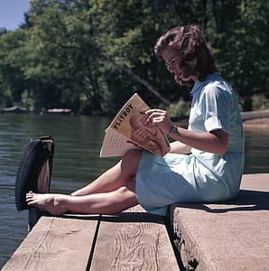 woman sitting on dock holding Playboy magazine thumbnail