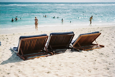 three brown wooden lounge chairs on beach thumbnail