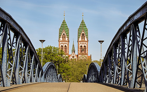 gray steel bridge with white and green castle in front thumbnail