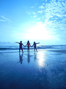 three children on the shoreline during daytime thumbnail