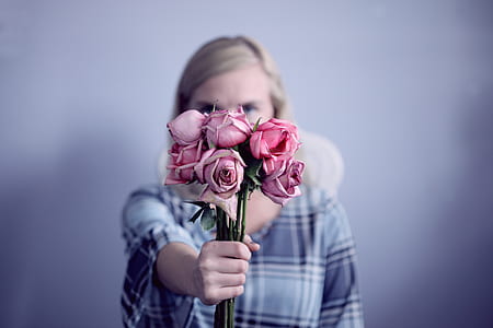 woman standing while holding pink rose flowers thumbnail