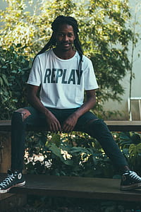 man sitting on bench near plants during daytime thumbnail