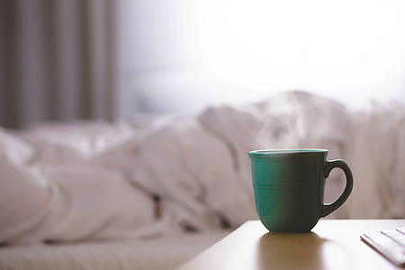 green teacup near white bed sheet thumbnail