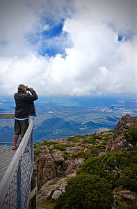 man standing on balcony viewing green landscape during daytime thumbnail