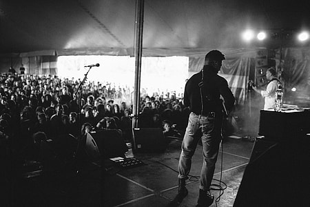 grayscale photo of musical band performing on stage with people watching thumbnail