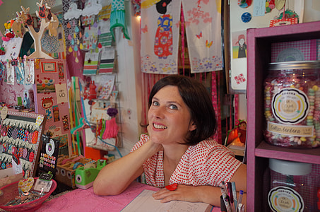 smiling brunette haired woman in red and white shirt with right hand on neck thumbnail