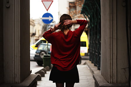 Woman in Red Sweater and Black Miniskirt Holding Hair Facing Road thumbnail