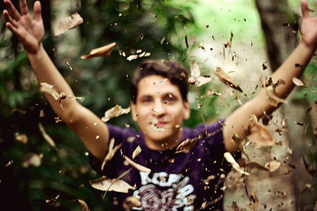 selective focus photography of man throwing brown dry leaves thumbnail