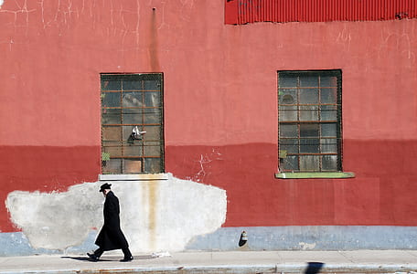 man walking beside red building thumbnail
