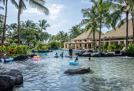 people swimming in body of water near cottages during daytime thumbnail