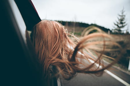brunette haired woman looking out of car window on road during daytime thumbnail