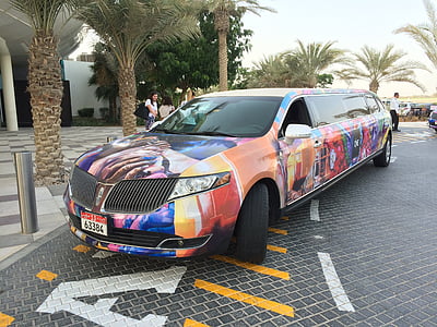 multicolored Lincoln limousine parked near white building thumbnail