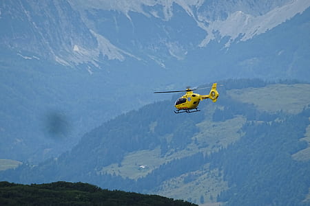 yellow helicopter flying above forests thumbnail