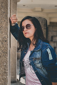 woman wearing blue denim jacket while leaning on concrete wall thumbnail