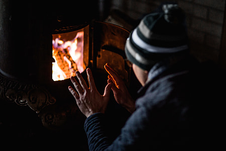 man in black jacket and green and white beanie in front of a furnace thumbnail