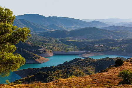 brown and green mountains near body of water during daytime thumbnail