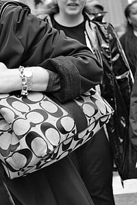 woman holding monogrammed Coach shoulder bag in grayscale photography thumbnail