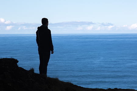 silhouette of man near body of water at daytime thumbnail