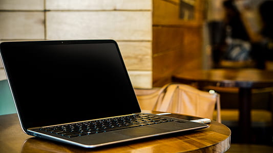 black laptop computer turned off on wooden table thumbnail