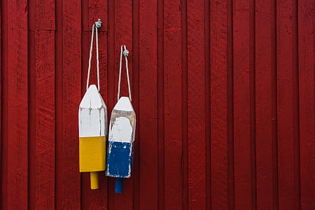two yellow and blue wooden decor hanging by red wall thumbnail