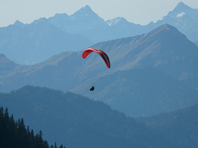 person in parachute above trees during daytime thumbnail