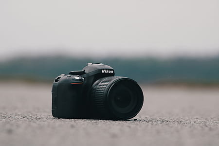black Nikon DSLR camera on ground thumbnail