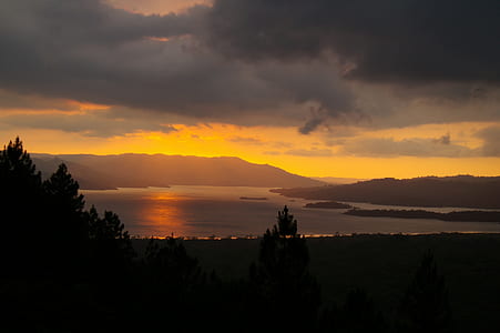 body of water near trees at sunset thumbnail