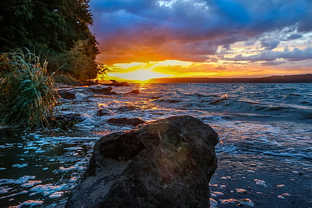 rock formation on body of water during sunset thumbnail