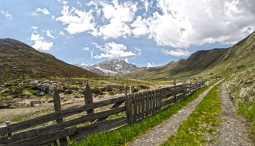 brown wooden fence at the foot of mountain under white and blue sky thumbnail