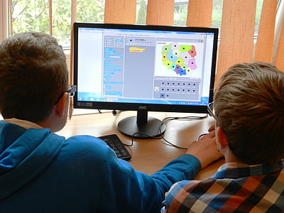 two boy playing computer beside clear glass window thumbnail