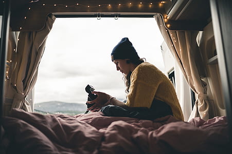 woman sitting on white bedspread holding black plastic toy thumbnail
