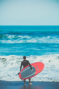 person holding red surfboard thumbnail