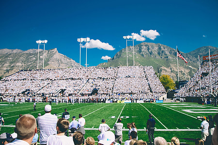 people watching football game under white clouds and blue sky at daytime thumbnail