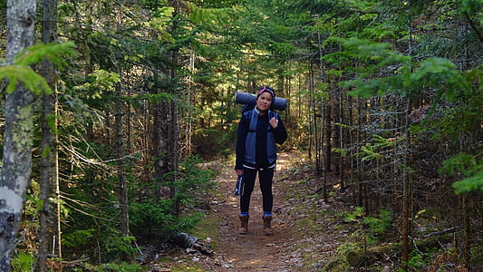 woman standing in between of tall trees thumbnail