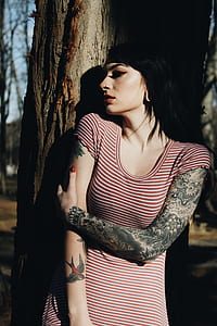 woman in black and white striped shirt leaning on tree branch thumbnail