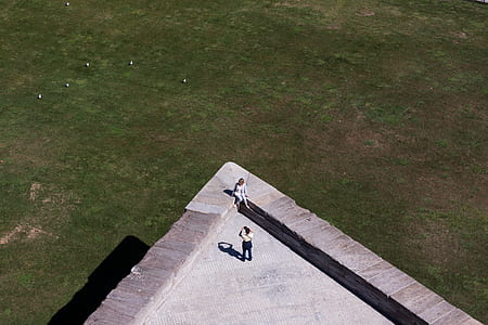 woman sitting at a corner of building roof while person taking photo of her during daytime thumbnail
