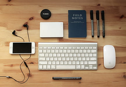 gold iPhone 5s beside Apple wireless keyboard and Mighty mouse on brown rustic table thumbnail