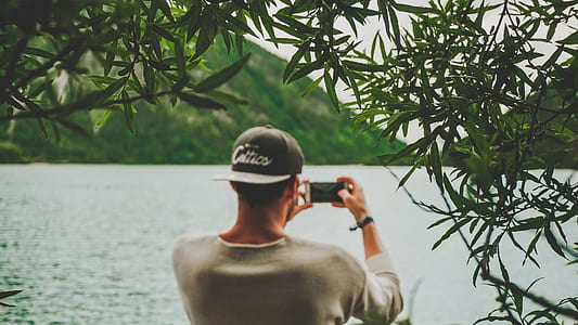 man taking photo of body of water using smartphone thumbnail