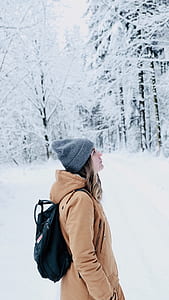 woman standing near snow covered trees during daytime thumbnail