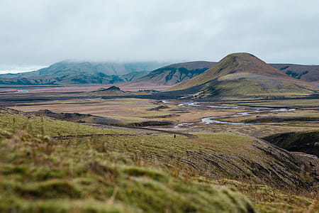 A hiker on a moss-grown volcanic hill on a cloudy day thumbnail