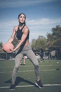 woman holding medicine ball on field doing fitness workout thumbnail