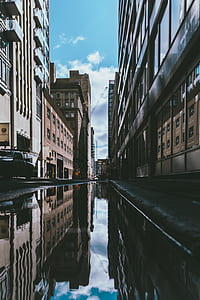 water on gray concrete road surrounded with buildings during daytime thumbnail