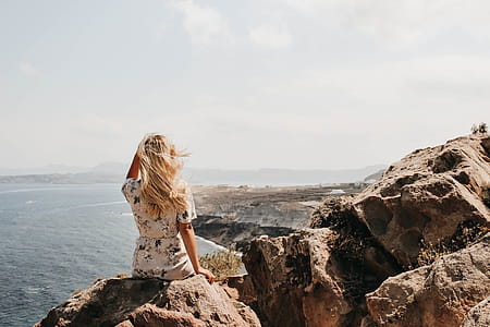 Woman Sitting on a Cliff Watching the Body of Water thumbnail
