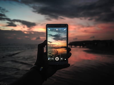 person taking photo of seashore during golden hour thumbnail