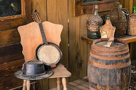 cowboy hat and string instrument on chair beside wine barrel thumbnail