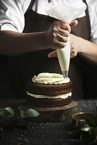 person putting cream on chocolate cake thumbnail
