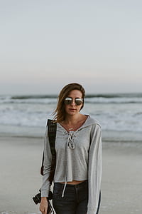woman in gray pullover hoodie wearing black sunglasses near body of water thumbnail