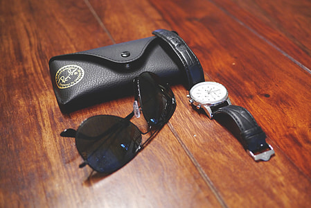 black Ray-Ban Aviators on wooden floor beside round silver-colored watch thumbnail